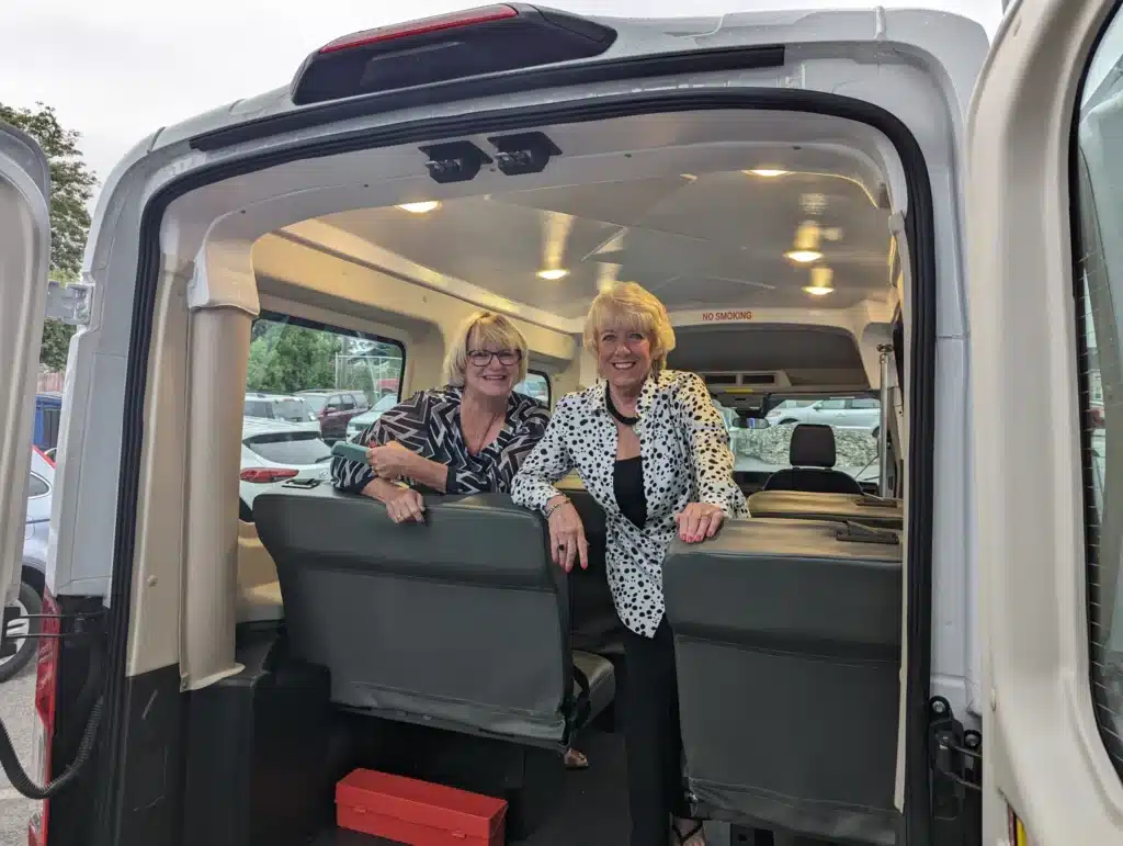 Foster Grandparent Leadership two staff members smiling in the back of the foster grandparent van